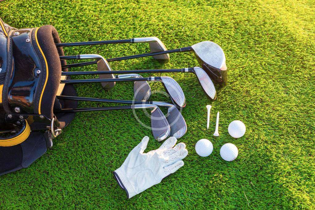 Golf clubs, balls, and gloves placed on the ground, ready for the next swing.