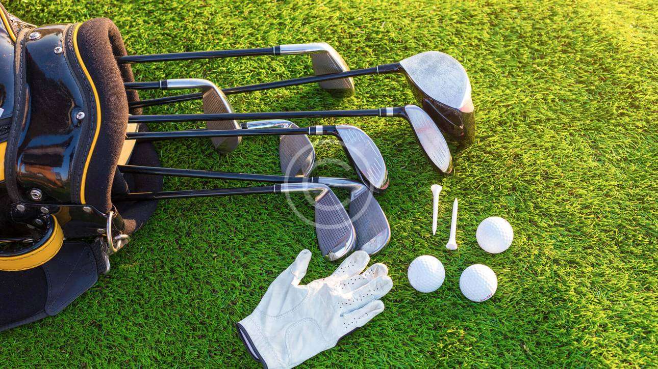 Golf clubs, balls, and gloves placed on the ground, ready for the next swing.
