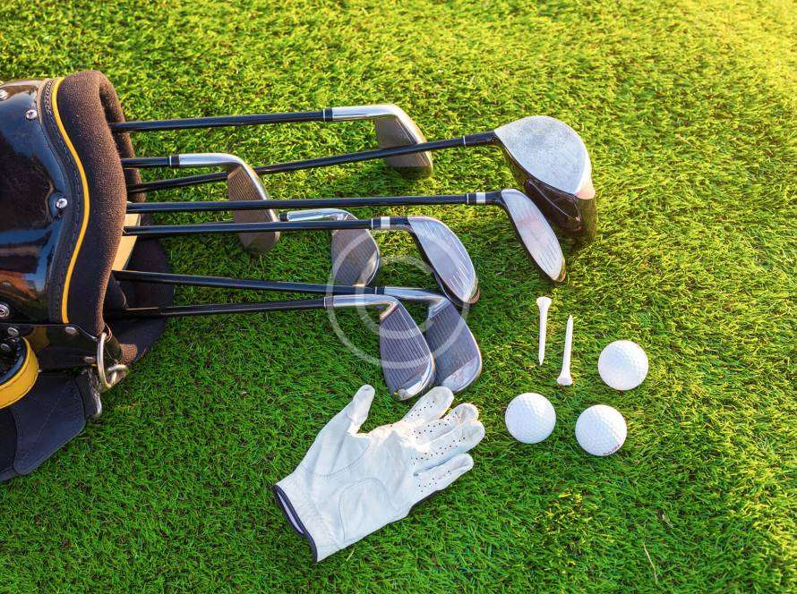 Golf clubs, balls, and gloves placed on the ground, ready for the next swing.