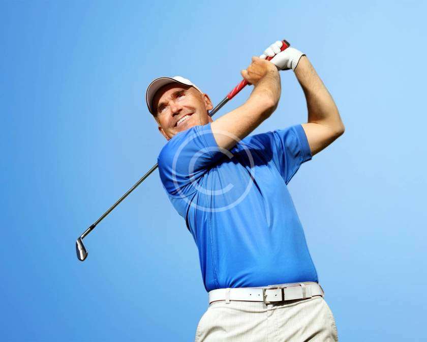 A man in a follow-through position with a golfing stick after hitting the ball, with a copyright logo.