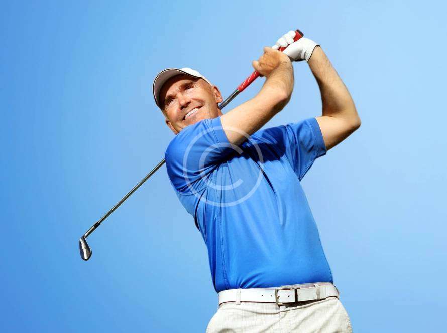 A man in a follow-through position with a golfing stick after hitting the ball, with a copyright logo.