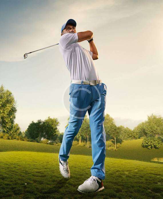 A man in a follow-through position with a golfing stick after hitting the ball, with a copyright logo.