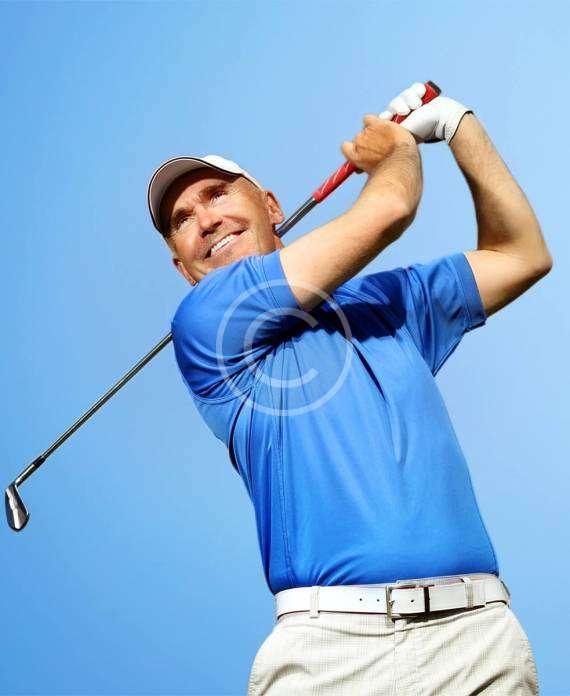 A man in a follow-through position with a golfing stick after hitting the ball, with a copyright logo.
