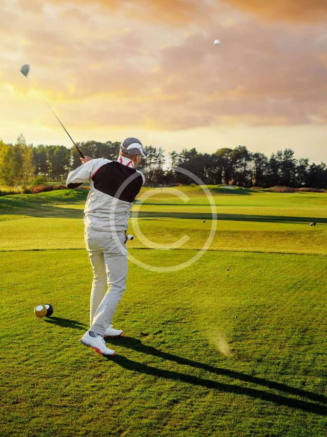 Male golfer hitting a shot after taking his position, focused on the ball.