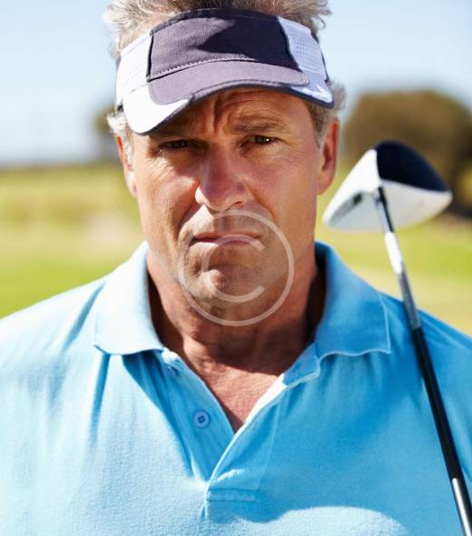 Man wearing a cap, holding a golf club with focus and determination.